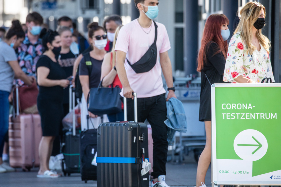 Reiserückkehrer stehen mit Mundschutz vor dem Corona-Testzentrum am Flughafen Stuttgart.