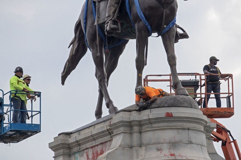 Workers remove the statue of Confederate General Robert E. Lee from a park in Charlottesville, Virginia on July 10, 2021.