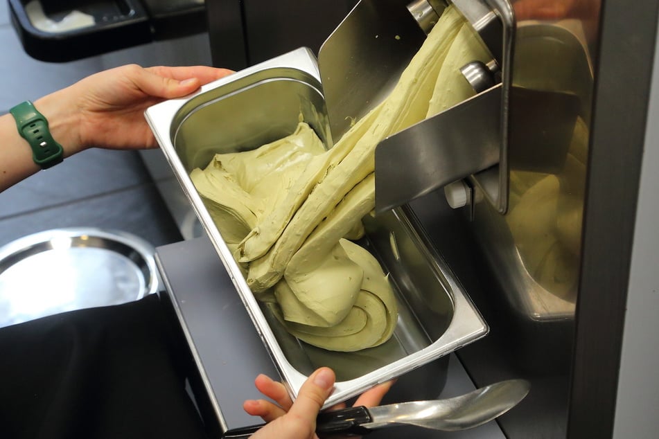 Das selbst produzierte Pistazien-Schokoladeneis wird in die Eiswanne gefüllt.