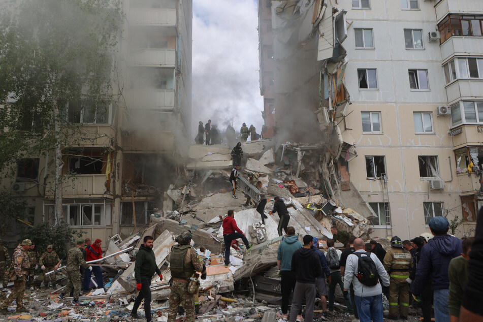 Firefighters and volunteers operate to secure the area on the site of a partially collapsed apartment building that was damaged by a Ukrainian strike in Belgorod.