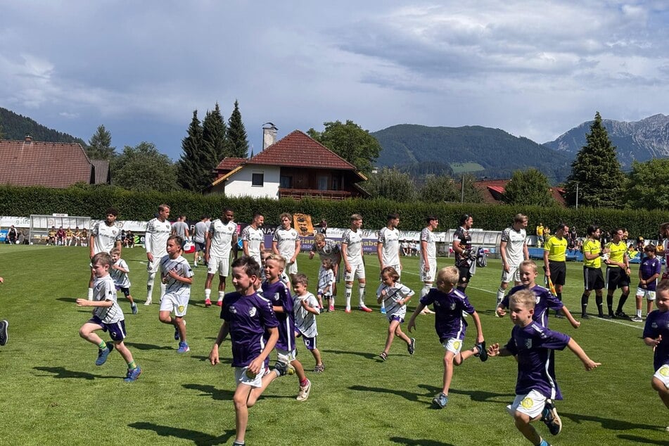 Die Einlaufkinder rennen vom Feld, die Mannschaften stehen bereit.