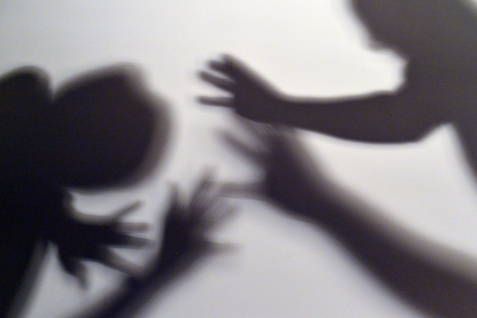 Das gestellte Bild zum Thema häusliche Gewalt symbolisiert, wie ein Kind versucht, sich vor der Gewalt eines Erwachsenen zu schützen. (Illustration)
