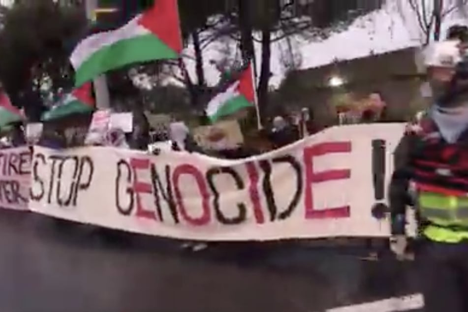 Prostesters hold a banner reading "Stop Genocide" as they shut down Travis Air Force Base in a rally against US funding for Israel's brutal assault on Gaza.