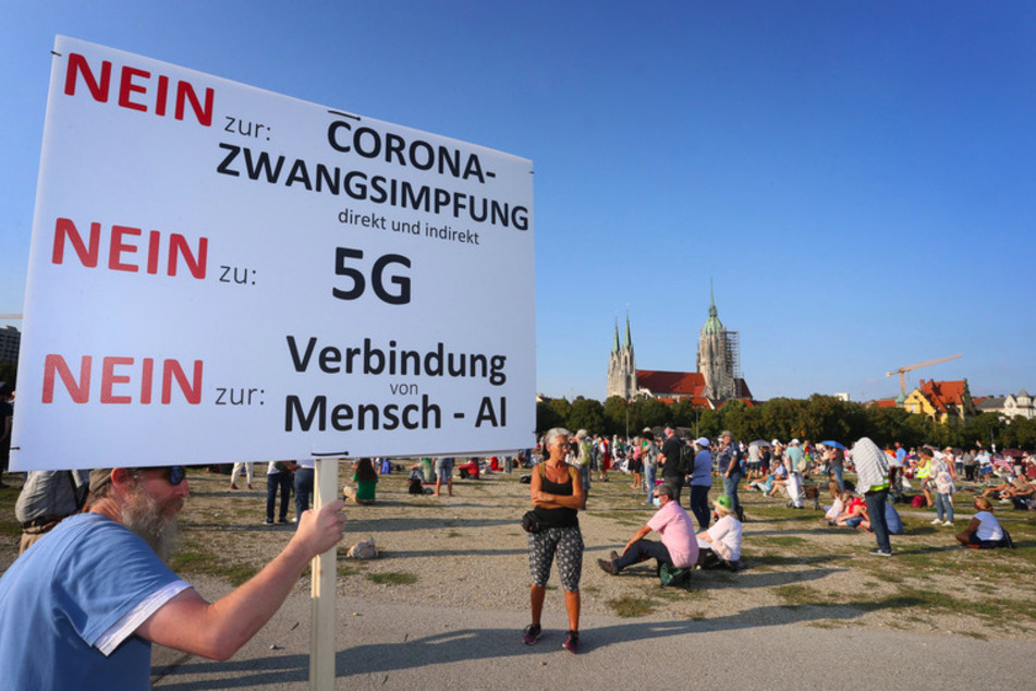 Auf der Theresienwiese hält ein Mann ein Plakat mit der Aufschrift "Nein zu Corona-Zwangsimpfung Nein zu G5 Nein zur Verbindung von Mensch -Al".