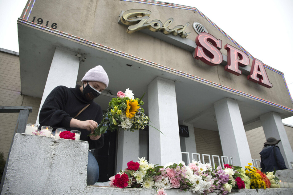 A woman arranges flowers at a memorial for the victims of the Atlanta spa shootings.