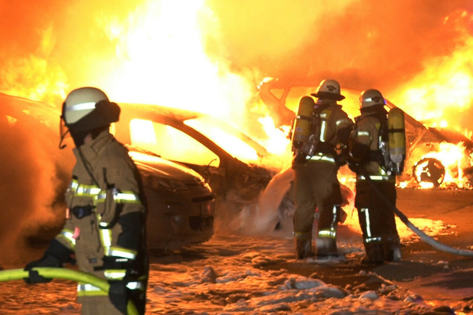 Einsatzkräfte der Feuerwehr löschen die brennenden Autos.
