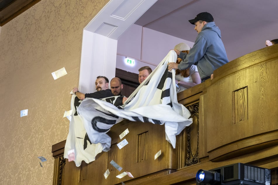 Die Störer entrollten Transparente. Zudem flatterten falsche Geldscheine in den Stadtrat.