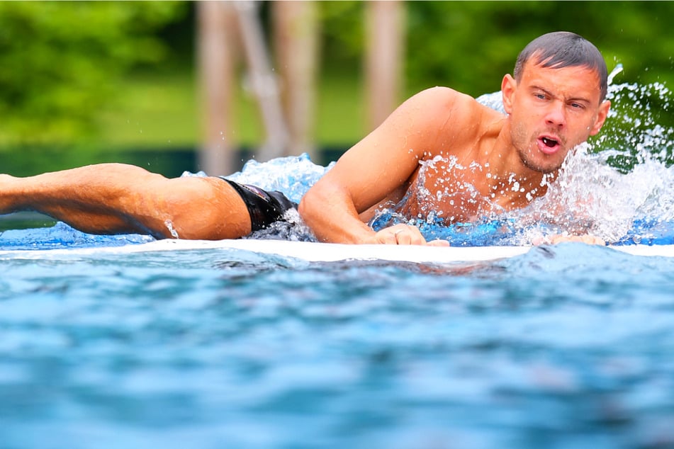 Chris Löwe (32) robbt sich nach seinem Sprung aus dem Wasser und kuschelte sich später in den wärmenden Bademantel.