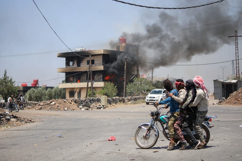Tribal and Bedouin fighters cross Walga town as they mobilize amid clashes with Druze gunmen, near the predominantly Druze city of Sweida in southern Syria on Saturday.