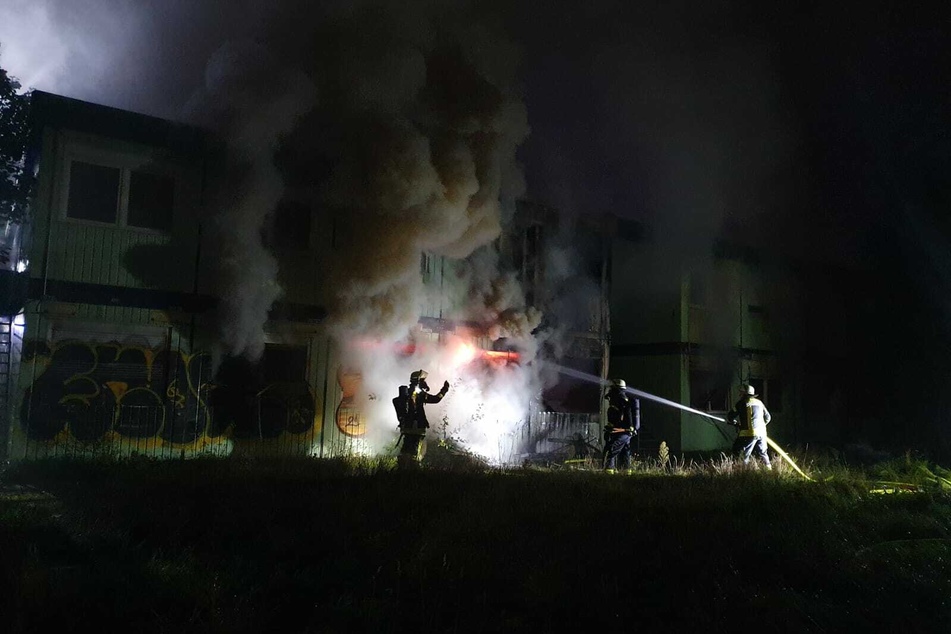 Feuerwehrleute löschen die brennende Flüchtlingsunterkunft.