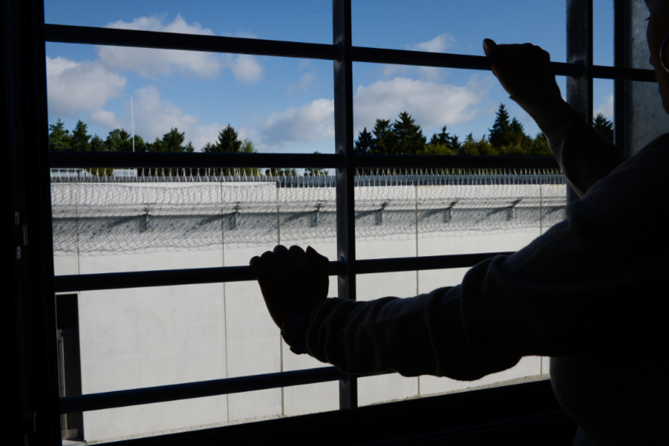 Ein Häftling steht in der Justizvollzugsanstalt an einem vergitterten Fenster in einer Zelle. (Symbolbild)
