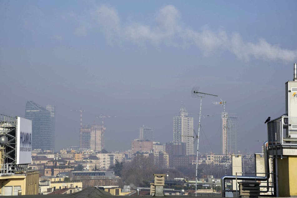 White smoke from chimneys hangs over the center of Milan, Italy.