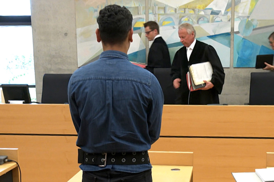 Der Angeklagte steht vor dem Richter-Pult.