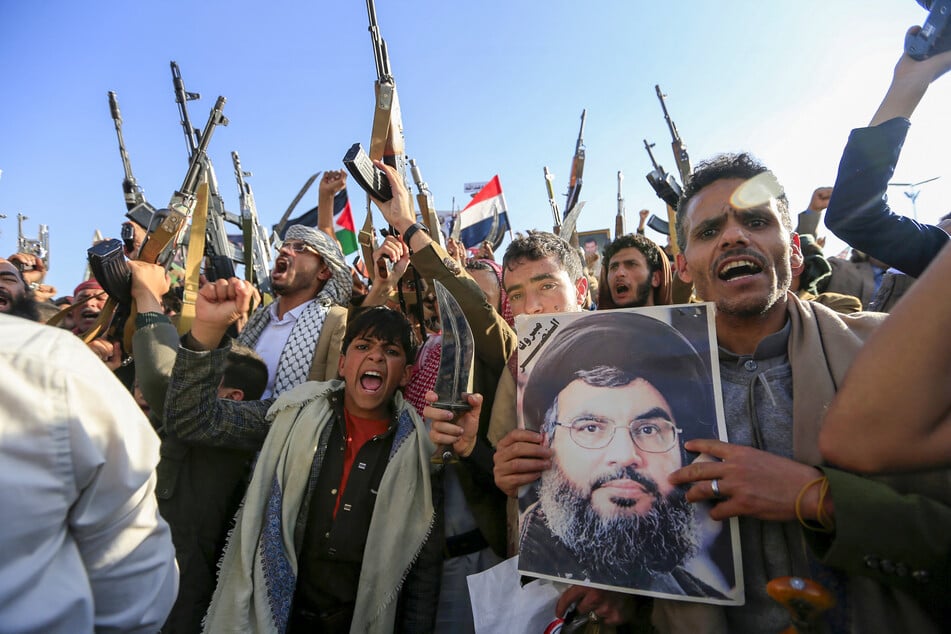 Yemenis brandish rifles and hold a picture of slain Hezbollah leader Hasan Nasrallah as they chant slogans during a rally in solidarity with Gaza in the Huthi-controlled capital Sanaa on November 29, 2024.