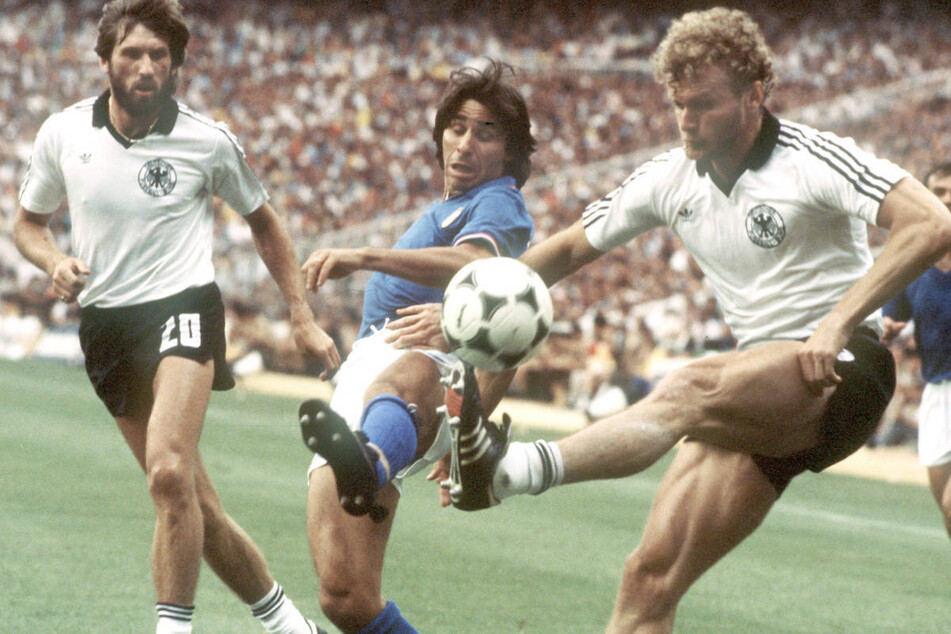 Der deutsche Abwehrspieler Hans-Peter Briegel (r.) und der italienische Stürmer Bruno Conti (M) liefern sich im Finale der Fußball-WM 1982 ein Duell um den Ball - im Hintergrund Manfred Kaltz. Die Italiener siegten mit 3:1 und wurden Weltmeister.