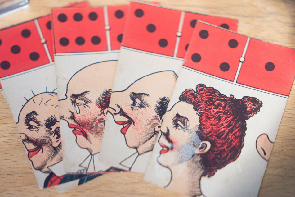 Karten aus dem Spiel "Caricaturen Domino“ (circa. 1900) des Verlags J.W. Spear und Söhne sind in einer Vitrine des Deutschen Spielarchivs zu erkennen.