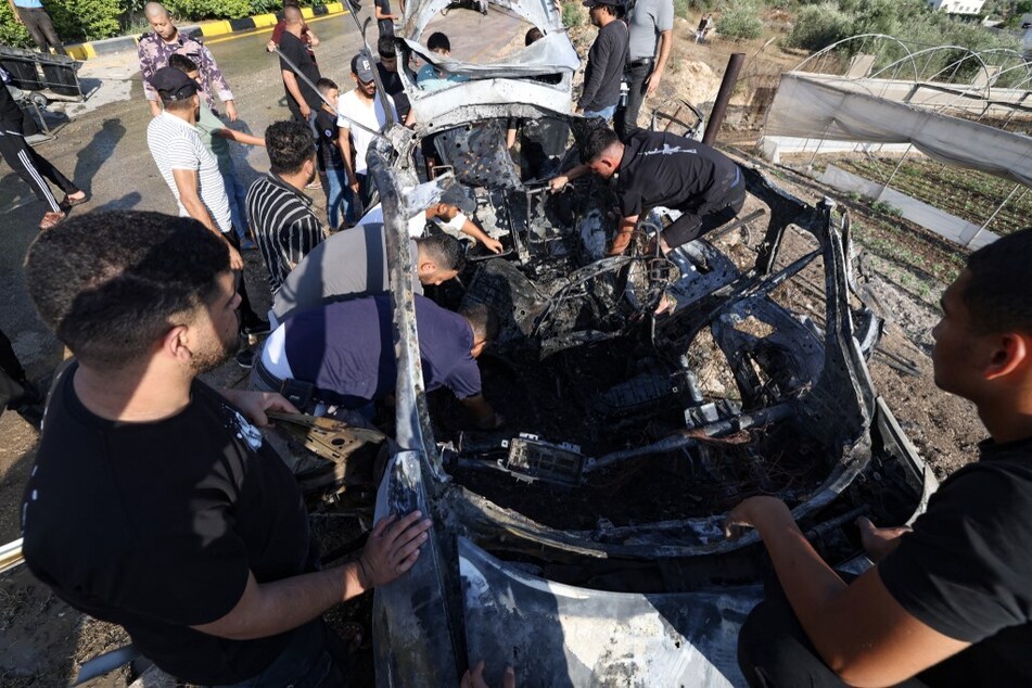 People check a car reportedly hit by an Israeli strike in the village of Zeita near Tulkarem in the occupied West Bank on August 3, 2024.