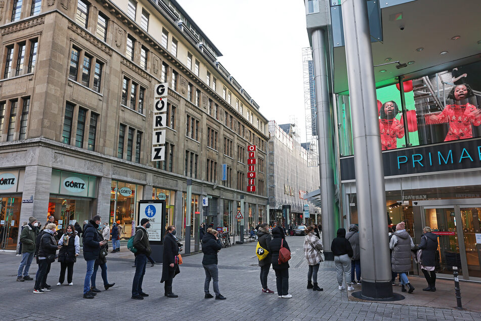 Kunden stehen an der 2G-Kontrolle am Eingang zu einem Kölner Geschäft in der Schlange.