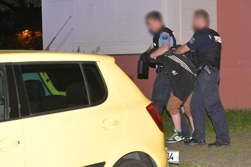 Polizisten führen einen der Verdächtigen ab.