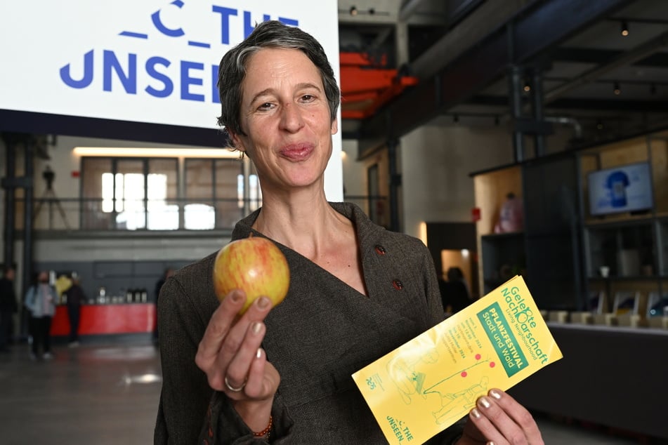 Projektleiterin Julia Naunin (50) mit einem Apfel und dem Flyer des Pflanzprojekts.