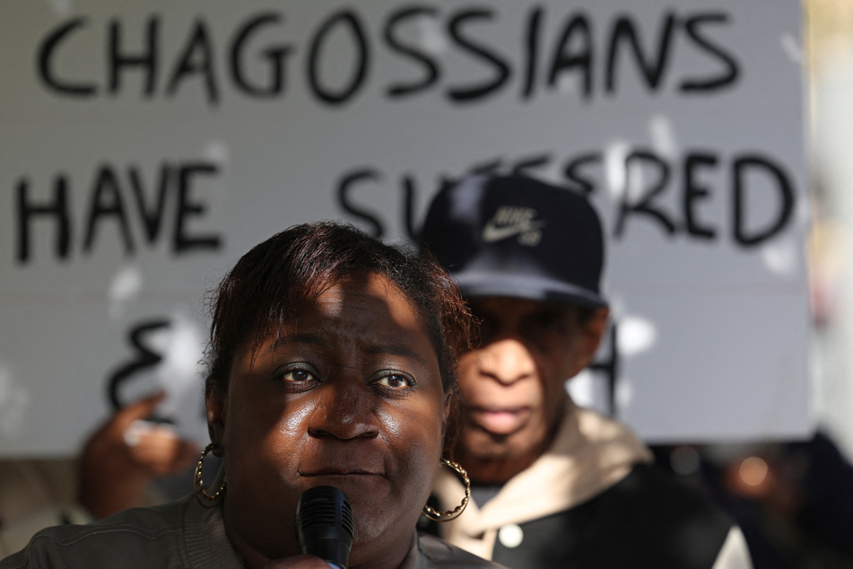 Members of the Chagossian community gather with banners and signs in a protest outside the UK parliament.