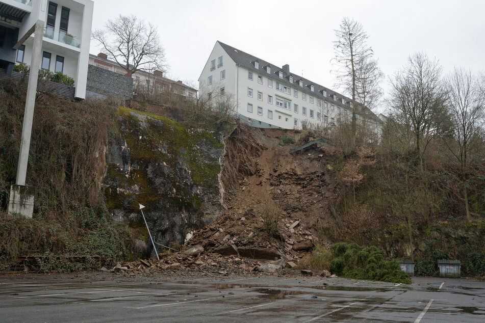 Geröll und Erde liegen unmittelbar nach dem Erdrutsch in einem Wohngebiet in Siegen auf einem unterhalb des Hanges gelegenem Parkplatz.
