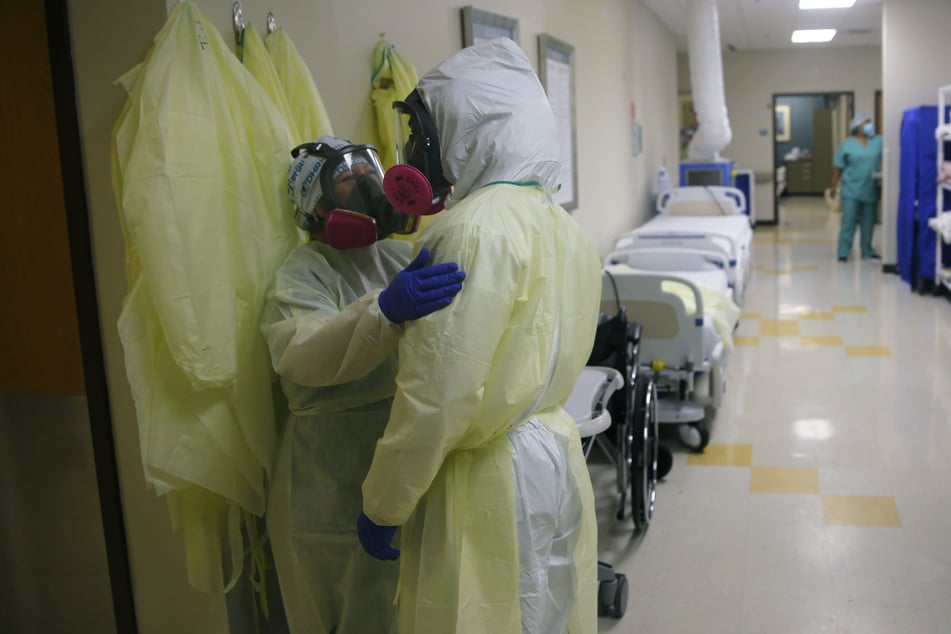 Medizinische Mitarbeiter von DHR Health in Schutzkleidung sprechen miteinander auf einem Flur einer Einrichtung in McAllen zur Betreuung von Covid-19-Patienten.