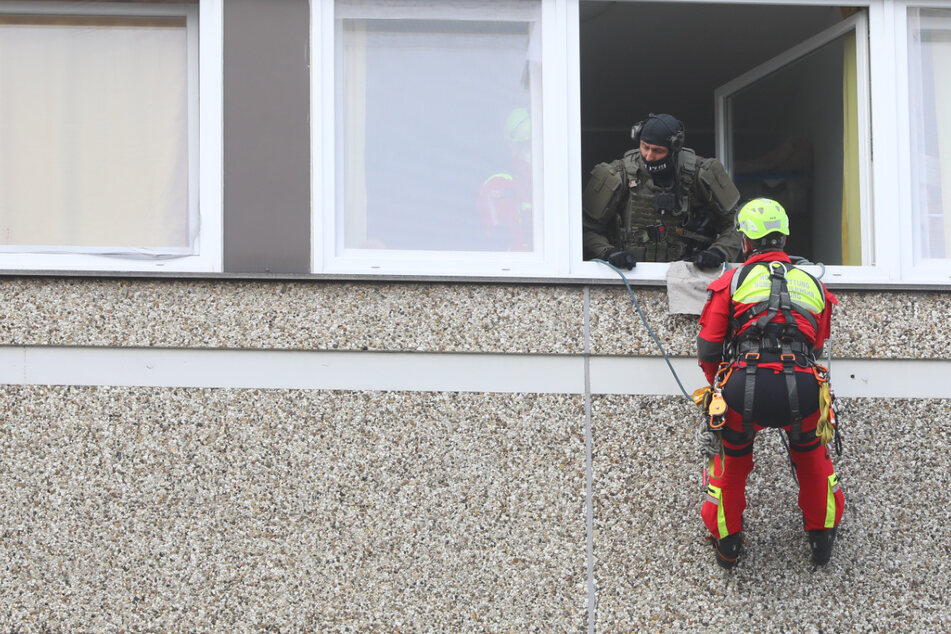 Rettungskräfte seilen sich vom Stockwerk über der Wohnung ab und versuchen mit der Mutter zu verhandeln.
