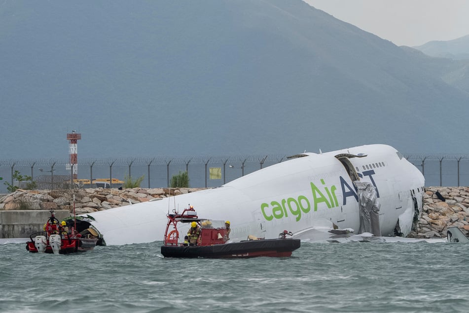 Rettungskräfte auf Booten inspizieren das verunglückte Frachtflugzeug.