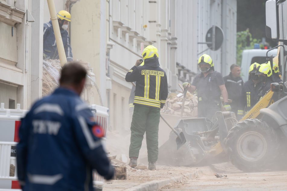 Einsatzkräfte der Feuerwehr und des Technischen Hilfswerks arbeiten sich durch Trümmerteile des eingestürzten Hauses.
