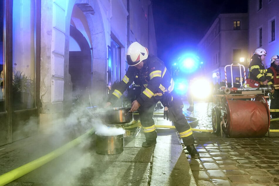Mit einem zweiten Edelstahl-Topf erstickt ein Feuerwehrmann den Fettbrand.