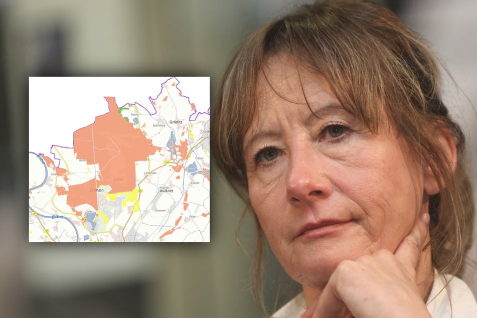 Heidemarie Russig vom Regionalen Planungsverband Oberes Elbtal/Osterzgebirge vor einem Ausschnitt der Karte für geeignete Waldstandorte für Windkraftanlagen, in der die Gohrischheide rot als Ausschlussgebiet gekennzeichnet ist.
