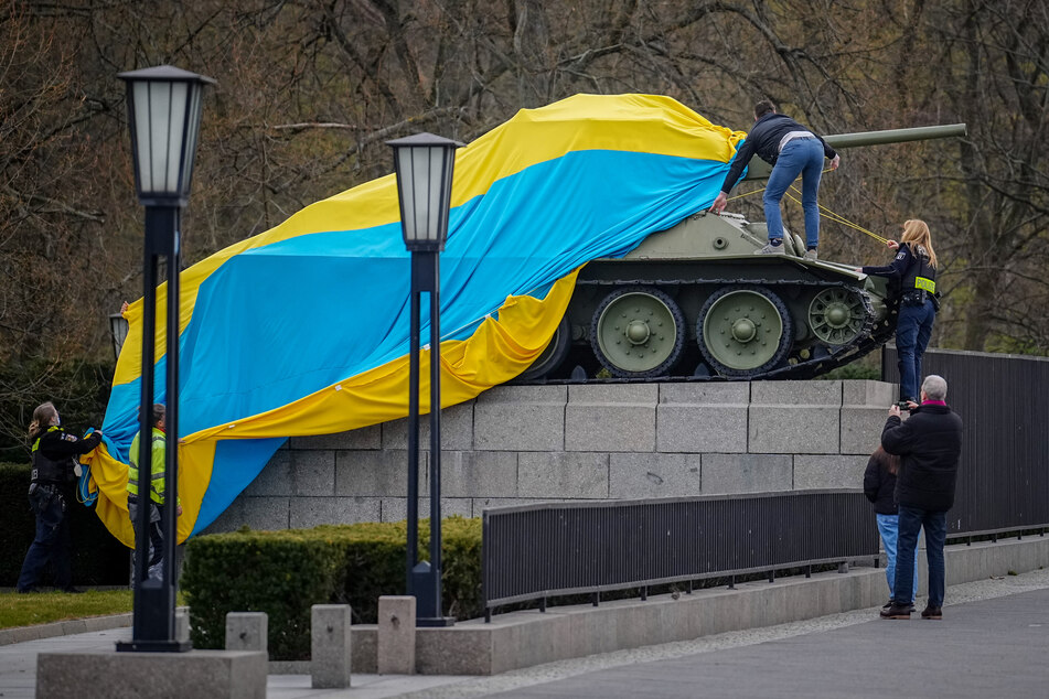 Der historische Panzer am Sowjetischen Ehrenmal in Berlin-Tiergarten ist mit einer ukrainischen Fahne bedeckt.