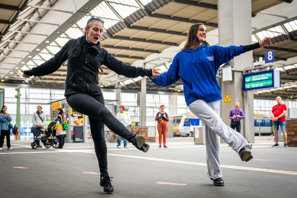Ballettdirektorin Sabrina Sadowska (l.) und die italienische Gasttänzerin Alice Ladino begrüßen die Zugfahrgäste im Bahnhof mit Sirtaki.