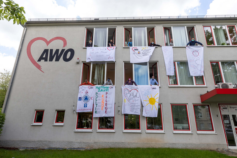 Am Verwaltungssitz machen AWO-Mitarbeiter mit bunten Stoff-Bannern ihrem Unmut Luft. Sie fordern Personal und faire Löhne vom Staat.