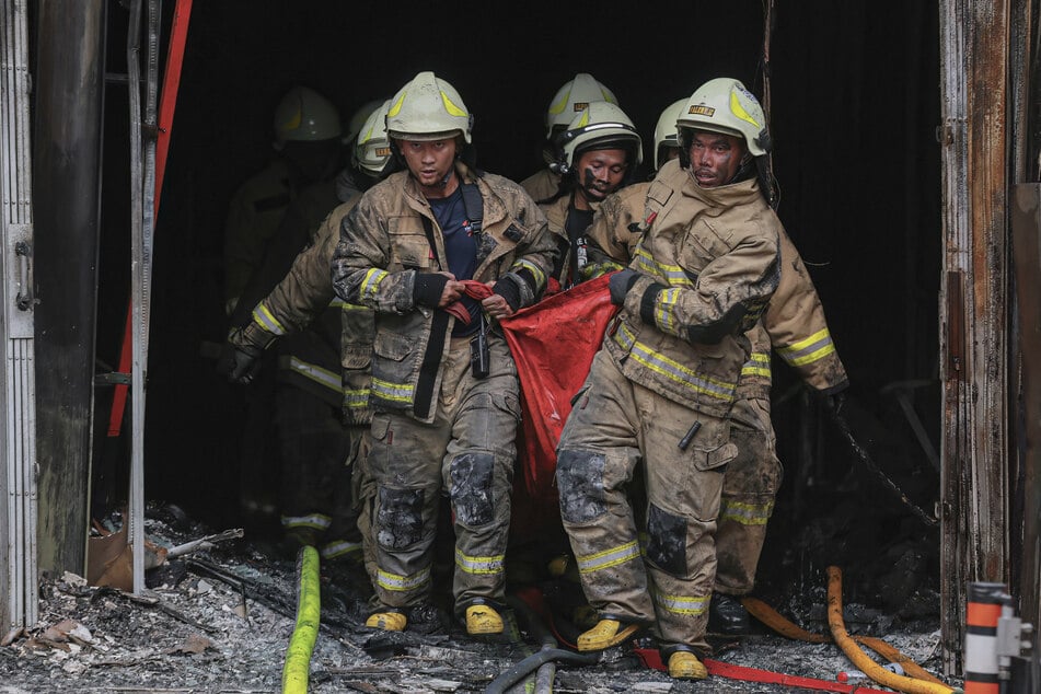 Feuerwehrleute tragen eine Leiche aus dem Feuerhaus, 22 Menschen kamen ums Leben.