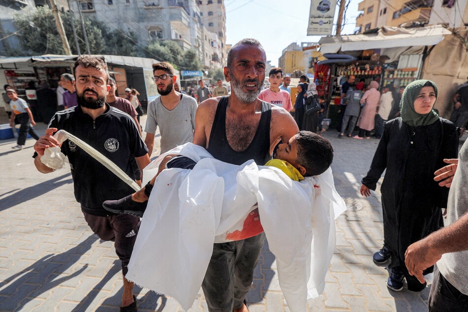 A man carries the body of a Palestinian child killed by Israeli bombardment on al-Bureij, outside al-Awda Hospital in Nuseirat in the central Gaza Strip, on September 21, 2025.