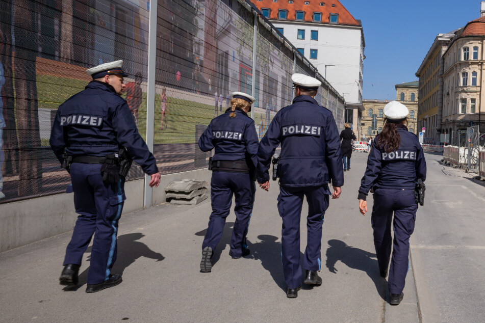 Vier Polizisten patroullieren durch eine fast leere Straße in der Münchner Innenstadt.