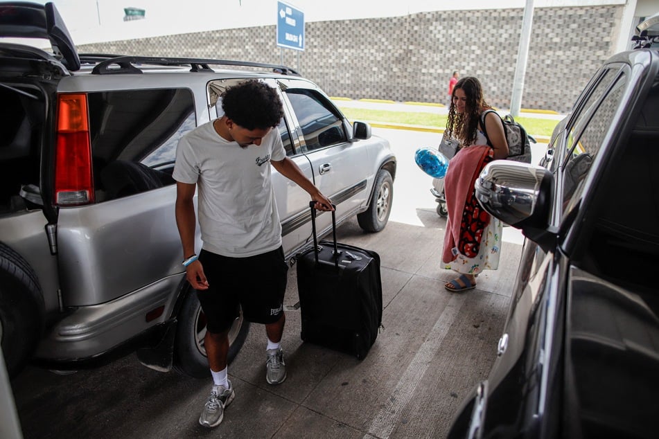 Emerson Colindres (l.) helps his sister Alison with her luggage upon her arrival at the Palmerola International Airport in Tegucigalpa, Honduras, on June 24, 2025.