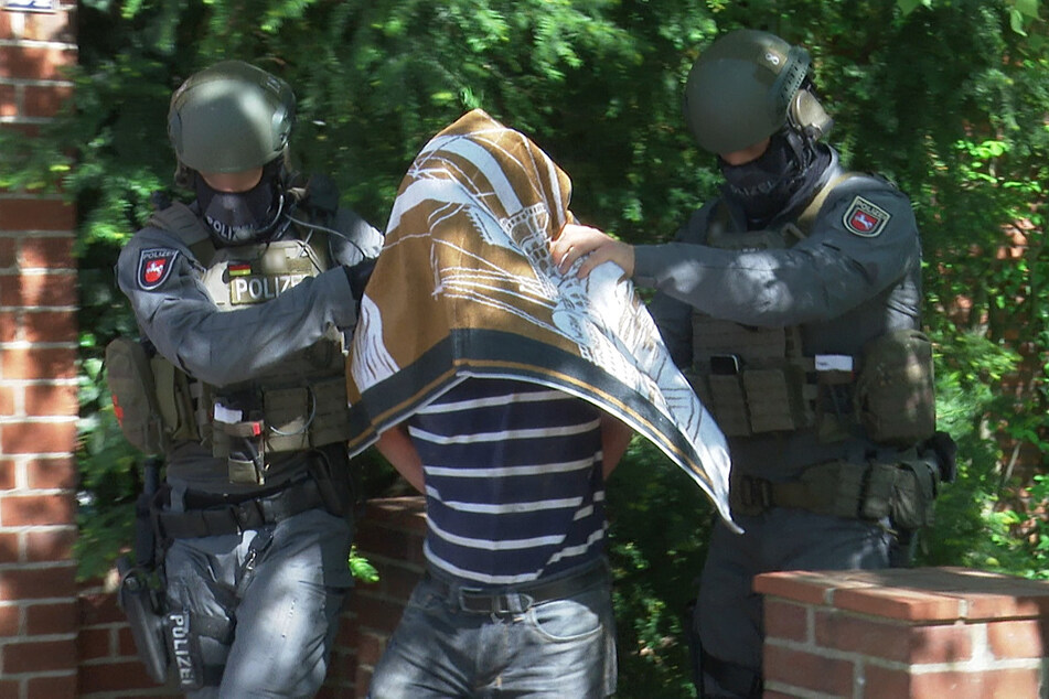 Polizisten führen nach einem Polizeieinsatz den Verdächtigen (53) in Handschellen ab.