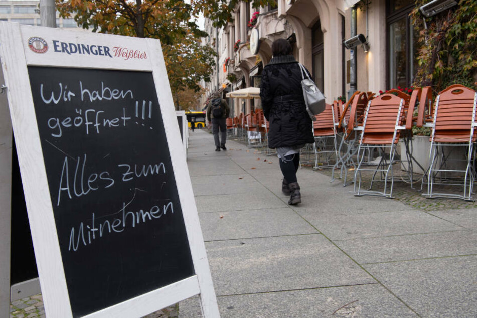 Eine Frau geht an hochgeklappten Stühlen vor einem Restaurant am Gendarmenmarkt vorbei. Laut Saleh ist der Mietendeckel während der Corona-Krise auch für etliche Branchen wie die Gastronomie hilfreich.