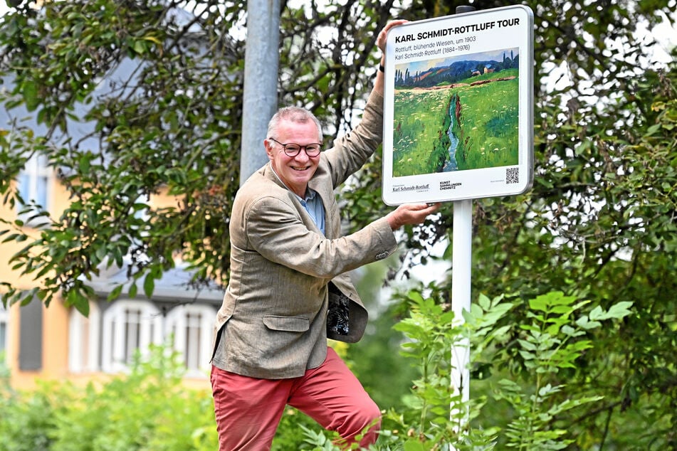 Buchautor Ralf W. Müller (66) zeigt ein Schild zum neuen Wanderweg mit passendem Gemälde.