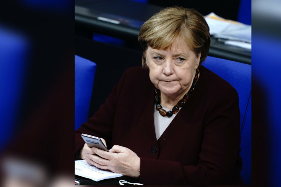 Bundeskanzlerin Angela Merkel (66, CDU) nimmt an der Sitzung des Bundestags nach ihrer Regierungserklärung zur Bewältigung der Corona-Pandemie teil und hält dabei ihr Smartphone in der Hand.