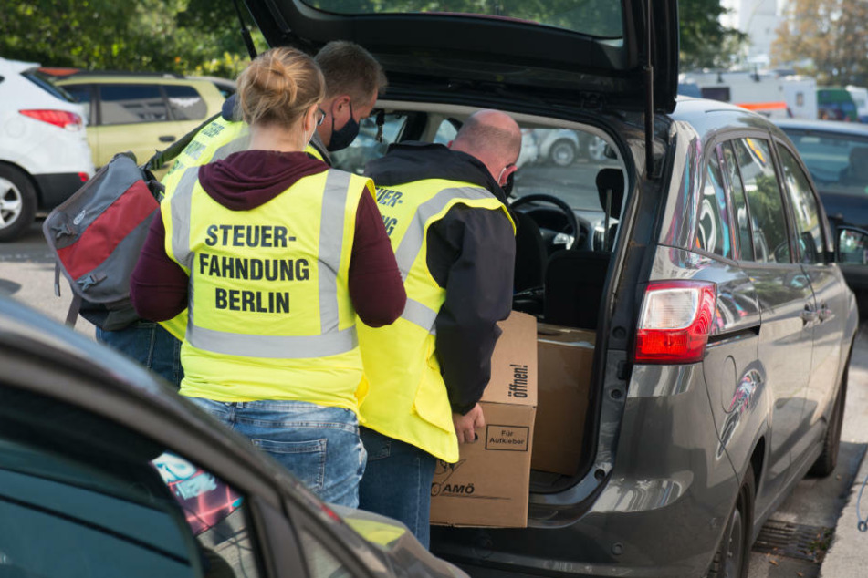 Beamte der Steuerfahndung verstauen Beweismaterial im Kofferraum eines Autos, das sie im Rahmen einer Durchsuchung in einem Geschäftshaus im Bezirk Treptow sichergestellt haben.