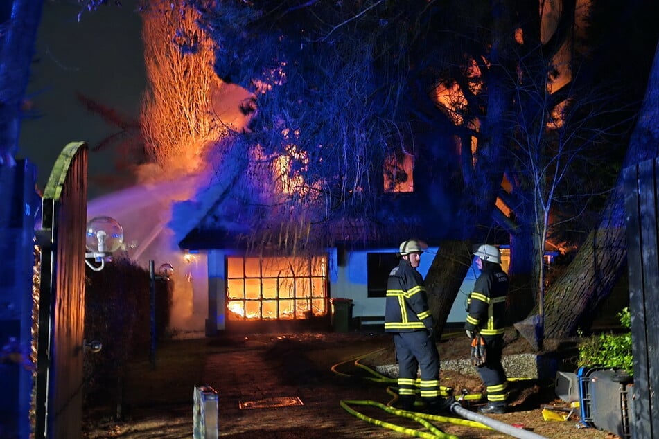 Einsatzkräfte der Feuerwehr stehen am Brandort in Hamburg-Schnelsen.