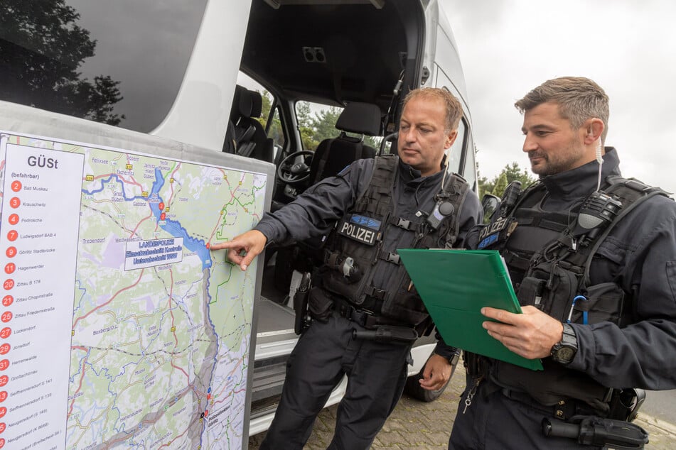 Zwei Ermittler der neuen Grenztruppe besprechen vor einer Karte des Einsatzgebietes ihr Vorgehen.