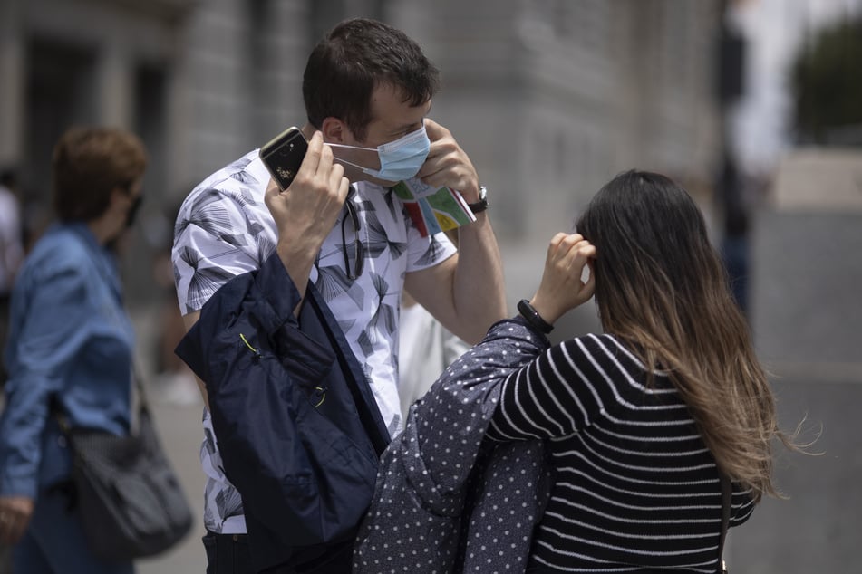 Ein Mann nimmt an der Puerta del Sol seine Maske ab. Die Maskenpflicht wird in Spanien ab Samstag erheblich gelockert.