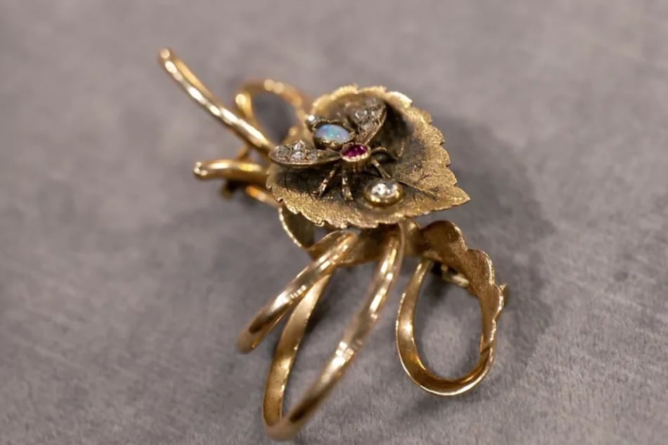 Das Schmuckstück aus 585er-Gold zeigt ein Blatt mit einer Fliege darauf, die sich an einem Wassertropfen zu erfrischen scheint.