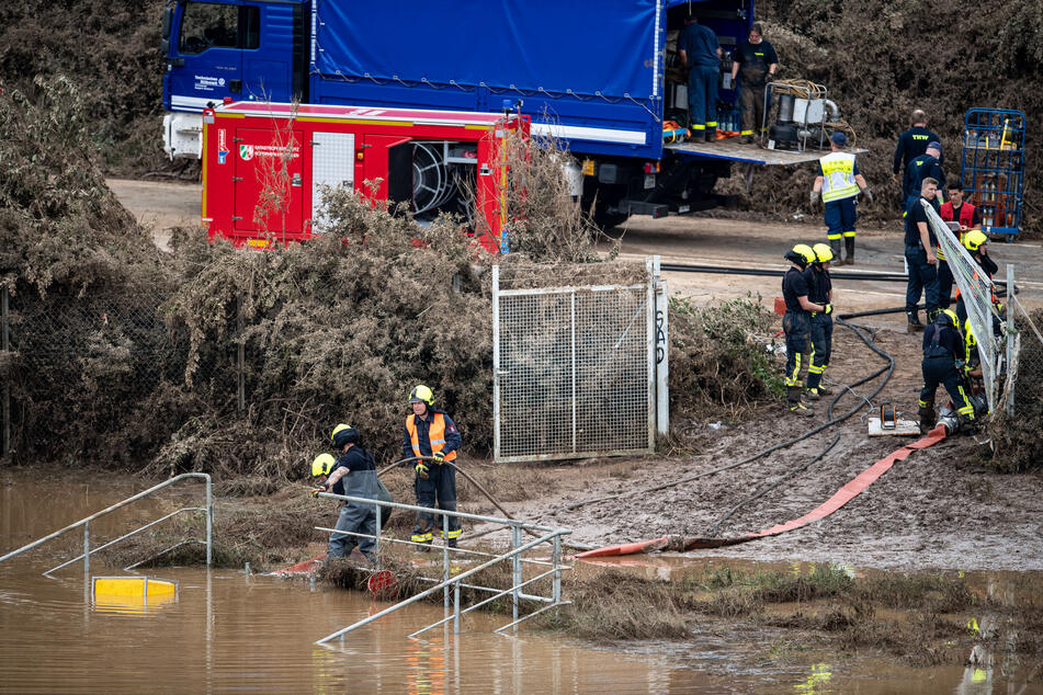 In Erftstadt pumpen Helfer von Feuerwehr und Technischem Hilfswerk (THW) Wasser aus einem Regenrückhaltebecken ab, in dem sich noch Fahrzeuge befinden sollen.