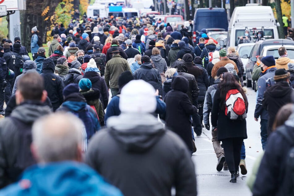 Die Teilnehmer des Protestzugs gegen Corona-Politik, der als "Schweigemarsch" bezeichnet wird, gehen über die Bornholmer Straße.